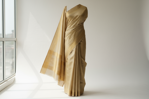 A graceful Bapta tussar saree in golden-beige tone, silk-cotton blend fabric with subtle sheen, minimalist studio setup — full-length product view, saree fully visible from top to bottom, centered composition, straight front angle, fits completely within frame height 60vh, no text, no watermark, no logo.